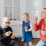 Family enjoying quality time blowing bubbles indoors, capturing joyful moments.